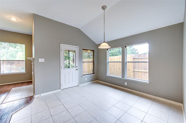 unfurnished dining area featuring lofted ceiling, plenty of natural light, baseboards, and light tile patterned floors