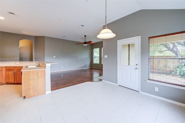 kitchen with lofted ceiling, visible vents, baseboards, and ceiling fan