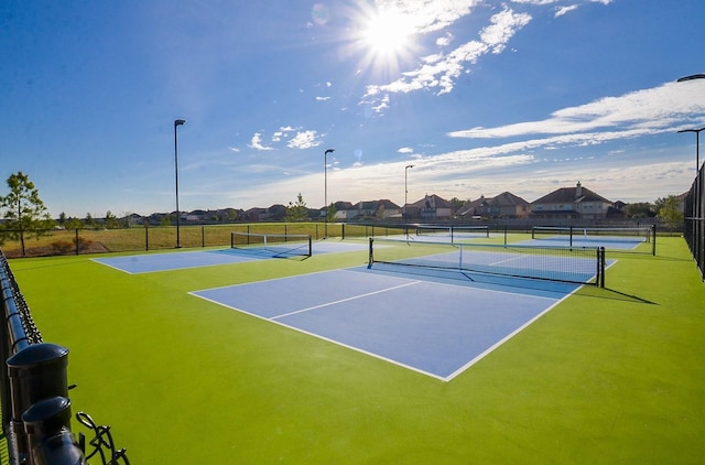 view of tennis court featuring fence, community basketball court, and a residential view