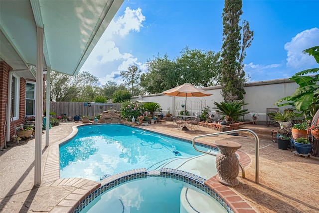 view of swimming pool featuring a pool with connected hot tub, a fenced backyard, and a patio area