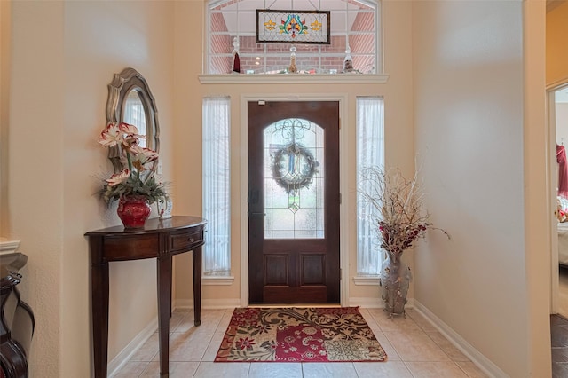 entrance foyer featuring tile patterned floors, baseboards, and a towering ceiling