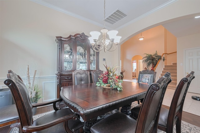 dining room with a notable chandelier, arched walkways, stairs, visible vents, and ornamental molding