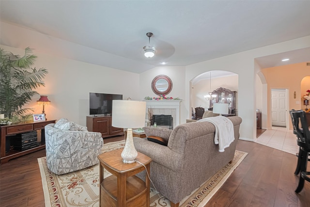 living room featuring arched walkways, ceiling fan with notable chandelier, and wood finished floors