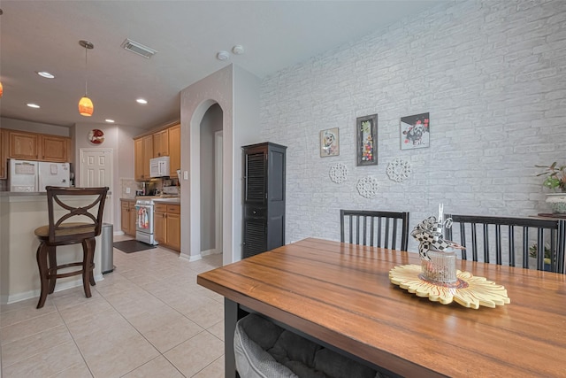 dining space featuring brick wall, recessed lighting, baseboards, light tile patterned floors, and visible vents