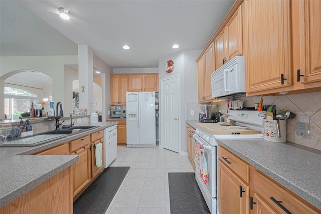 kitchen with light tile patterned flooring, a sink, white appliances, arched walkways, and backsplash