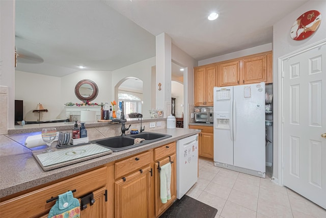 kitchen featuring light tile patterned flooring, white appliances, light countertops, arched walkways, and a sink