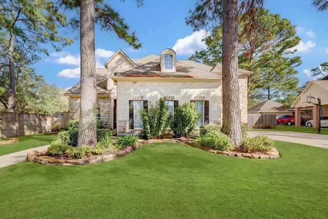 view of front facade featuring concrete driveway, stone siding, a front lawn, and fence