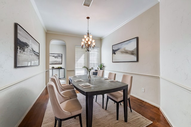 dining room featuring wood finished floors, visible vents, a notable chandelier, and crown molding