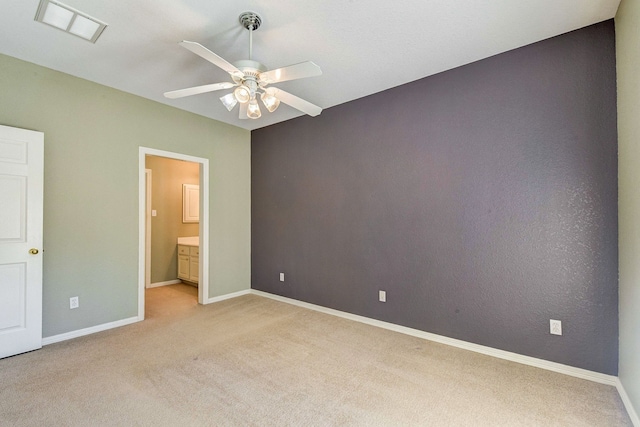 unfurnished bedroom featuring light carpet, visible vents, baseboards, ceiling fan, and ensuite bath