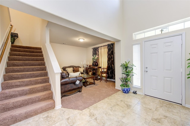 carpeted entrance foyer with baseboards and stairway
