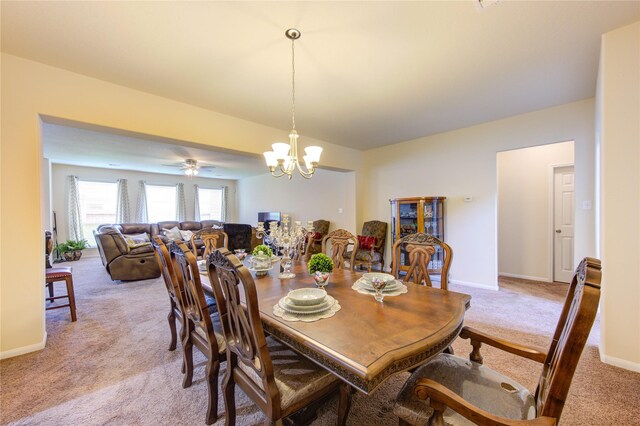 dining room featuring light carpet, baseboards, and a notable chandelier