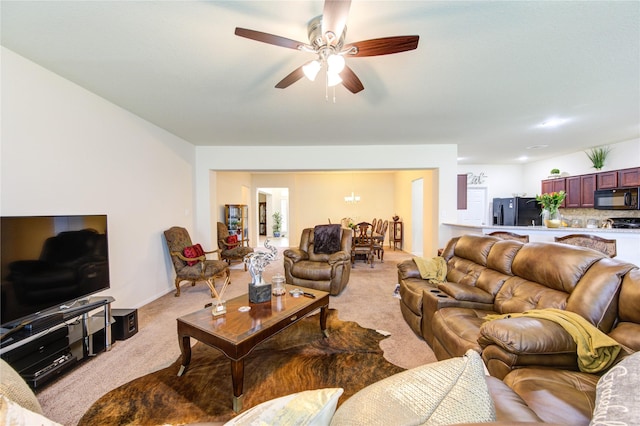 living room with ceiling fan with notable chandelier and light colored carpet