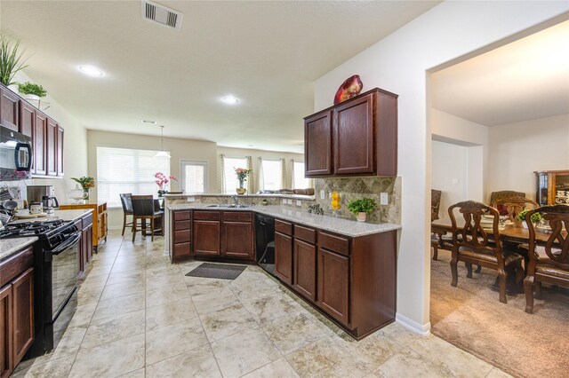 kitchen featuring a sink, black appliances, decorative backsplash, a wealth of natural light, and visible vents