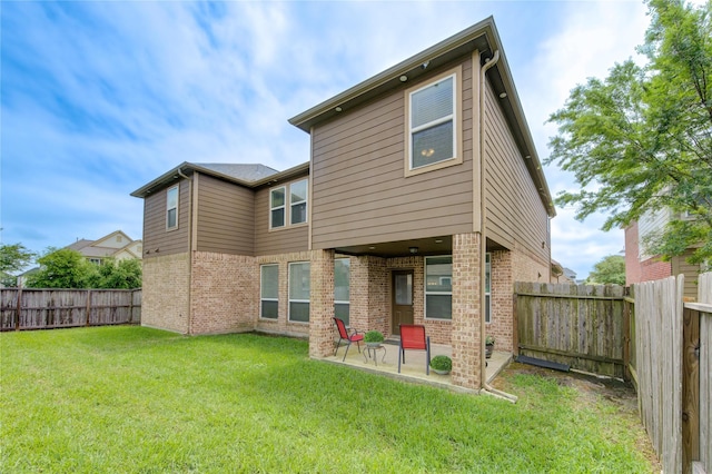 back of house with brick siding, a patio area, a lawn, and a fenced backyard
