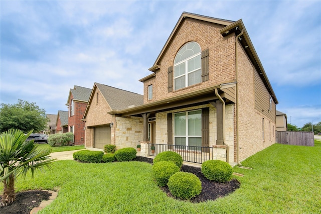 traditional-style house with a front lawn, stone siding, a porch, a garage, and brick siding