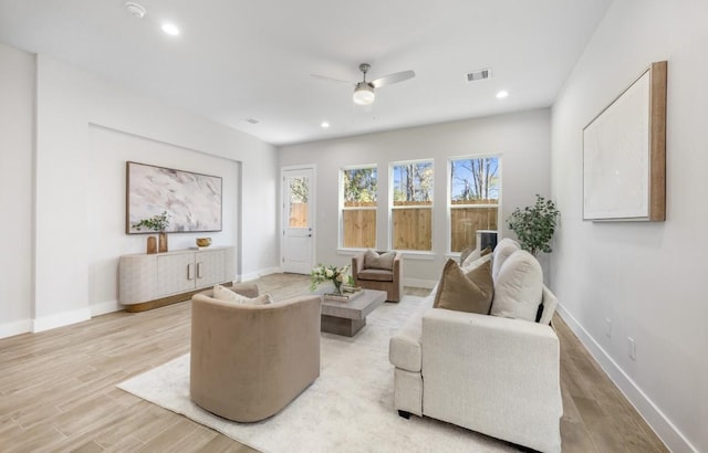living area with ceiling fan, baseboards, light wood finished floors, and visible vents