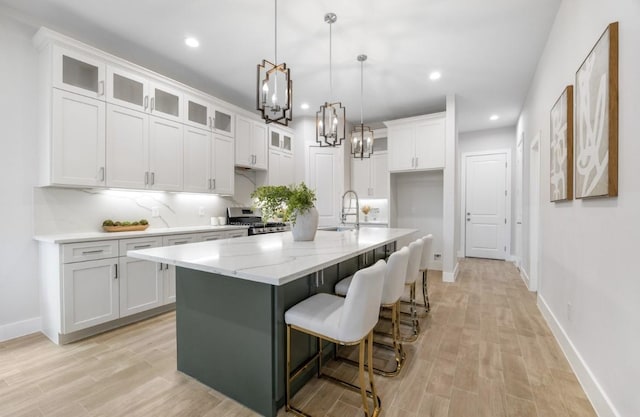 kitchen featuring white cabinets, light wood-style flooring, a sink, and stainless steel gas range