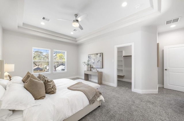 bedroom featuring a spacious closet, carpet flooring, a tray ceiling, and visible vents