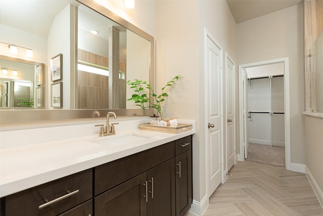 full bathroom featuring a walk in closet, vanity, and baseboards