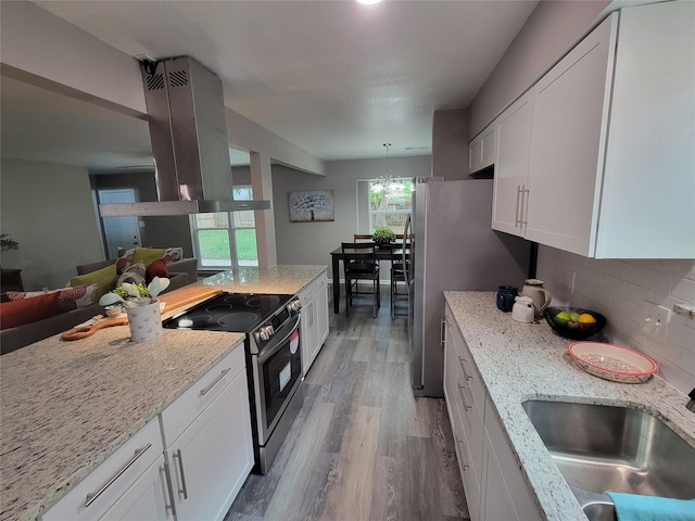 10654 Mayfield Rd, Houston, TX 77043 - kitchen featuring a sink, island range hood, wood finished floors, light stone counters, and appliances with stainless steel finishes