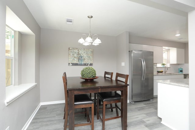 10654 Mayfield Rd, Houston, TX 77043 - dining area featuring baseboards, an inviting chandelier, visible vents, and light wood-type flooring