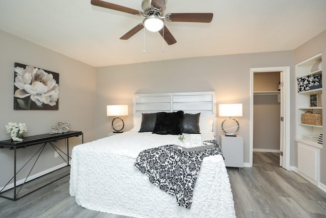 10654 Mayfield Rd, Houston, TX 77043 - bedroom featuring a ceiling fan, wood finished floors, a closet, a walk in closet, and baseboards