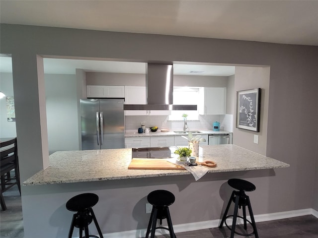 10654 Mayfield Rd, Houston, TX 77043 - kitchen with island exhaust hood, tasteful backsplash, white cabinetry, a breakfast bar, and appliances with stainless steel finishes