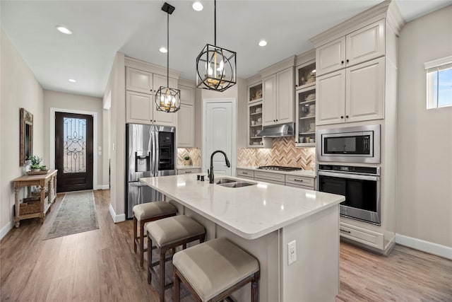 kitchen with a kitchen breakfast bar, baseboards, appliances with stainless steel finishes, and a sink