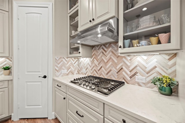 3105 Magnolia Knoll Ln, Houston, TX 77080 - kitchen with stainless steel gas cooktop, white cabinetry, decorative backsplash, under cabinet range hood, and glass insert cabinets