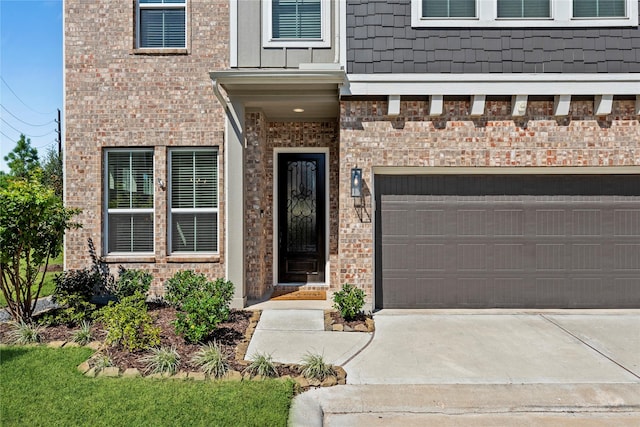 view of exterior entry featuring brick siding, an attached garage, and driveway