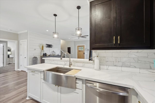 kitchen with light stone counters, dishwasher, ornamental molding, a sink, and tasteful backsplash