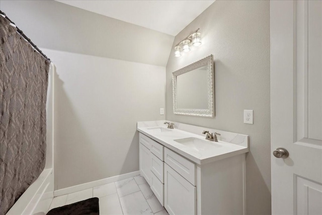 bathroom with baseboards, a sink, marble finish floor, and double vanity