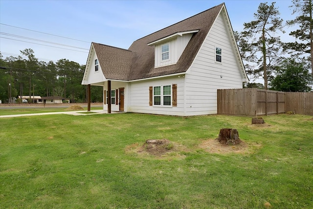 view of front of property featuring fence, a shingled roof, and a front yard