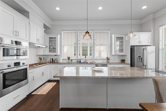kitchen featuring a center island, a sink, white cabinetry, appliances with stainless steel finishes, and ornamental molding
