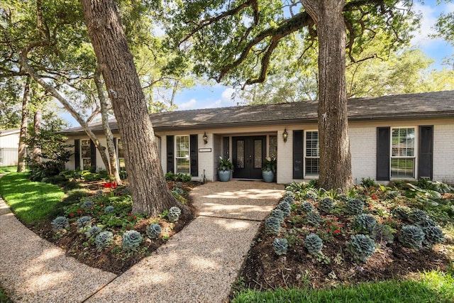single story home featuring brick siding and french doors