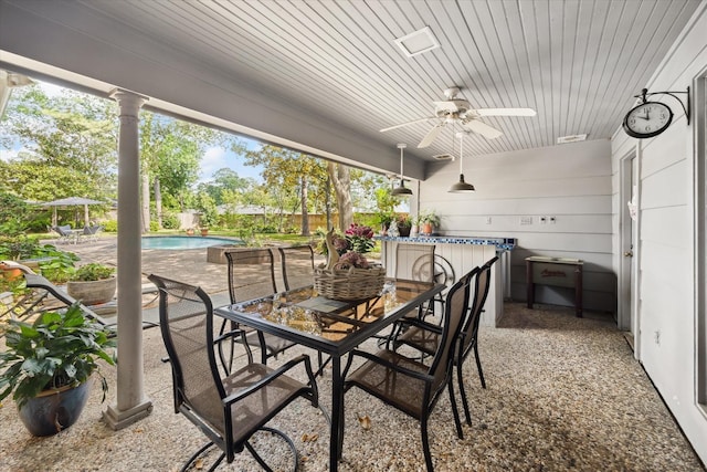 view of patio with outdoor dining area, ceiling fan, and an outdoor pool