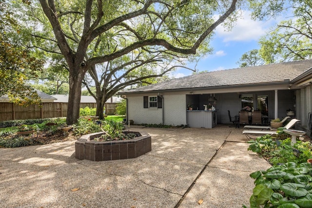 back of house featuring brick siding, a patio area, and fence