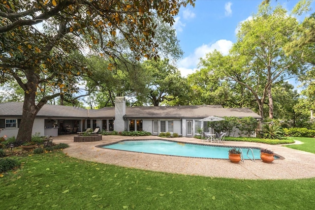 outdoor pool featuring a lawn and a patio area