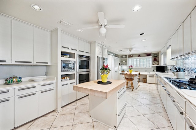 kitchen featuring recessed lighting, wood counters, stainless steel appliances, ceiling fan, and a center island