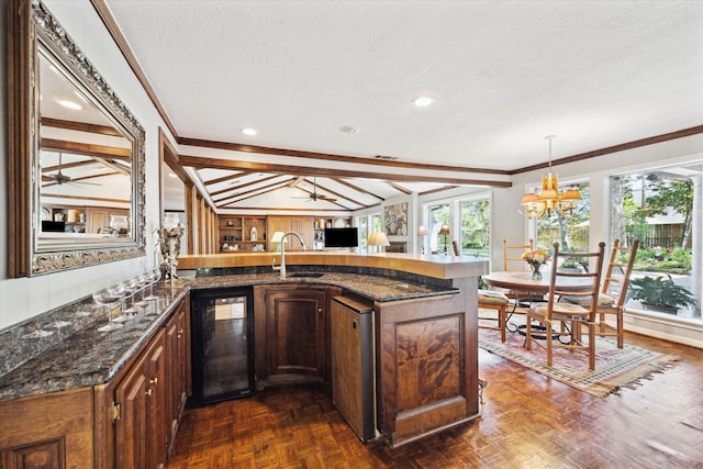 interior space with wine cooler, a textured ceiling, hanging light fixtures, and ceiling fan with notable chandelier