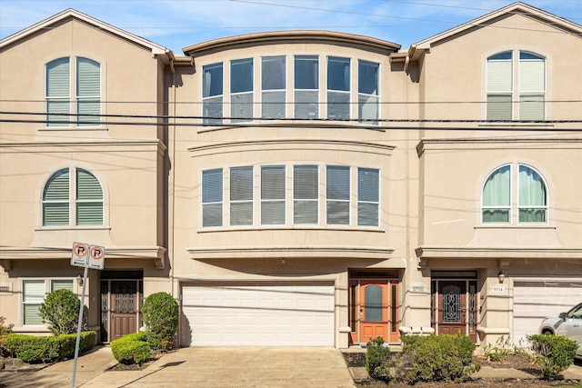 view of front of home with a garage, concrete driveway, and stucco siding