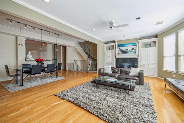 living area featuring wood finished floors, stairway, ceiling fan, track lighting, and ornamental molding