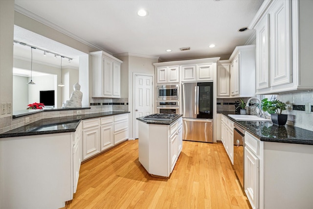 kitchen featuring white cabinets, ornamental molding, a sink, and appliances with stainless steel finishes