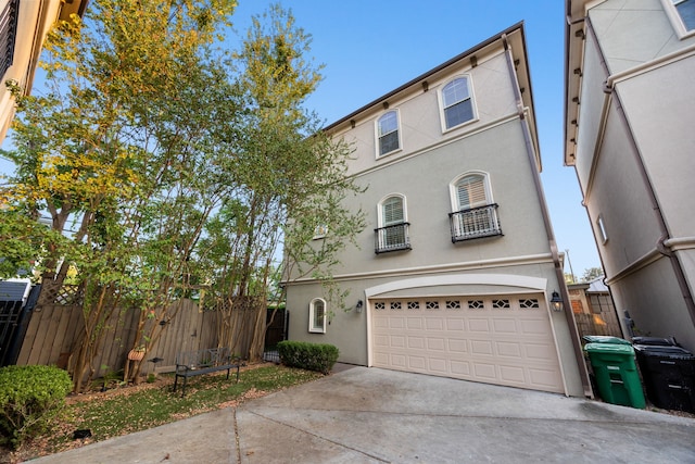 view of front of property featuring stucco siding, an attached garage, driveway, and fence