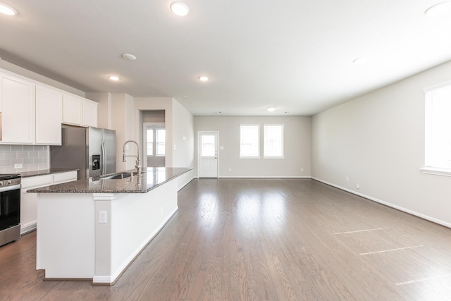 kitchen featuring stainless steel appliances, a kitchen island with sink, a sink, recessed lighting, and white cabinetry