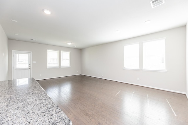 unfurnished living room featuring baseboards, visible vents, and dark wood-style flooring