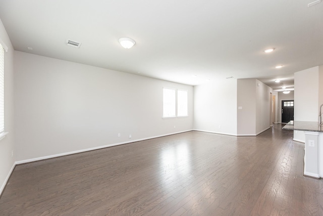 unfurnished living room featuring dark wood finished floors, visible vents, and baseboards