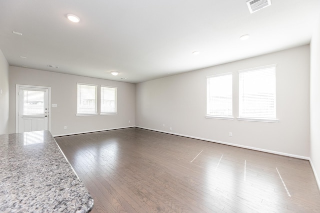 unfurnished living room featuring baseboards, dark wood-type flooring, and visible vents