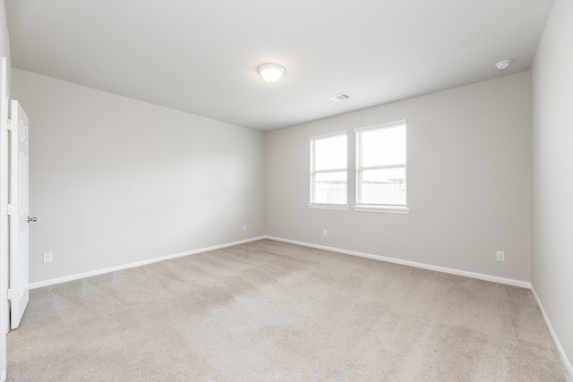 empty room featuring baseboards, visible vents, and light colored carpet