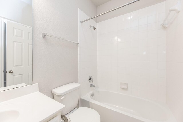 bathroom with toilet, a textured wall, vanity, and bathtub / shower combination